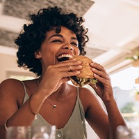 Woman smiling while enjoying burger at restaurant