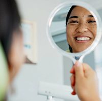 Woman smiling at reflection in dentist office