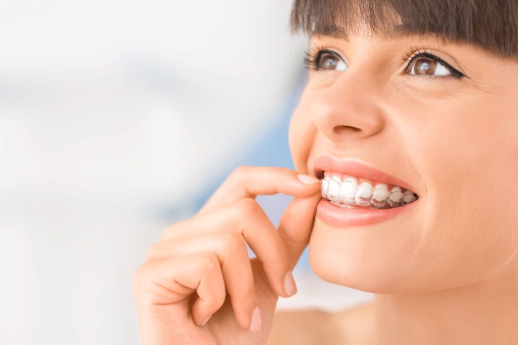 A woman putting on an Invisalign aligner.